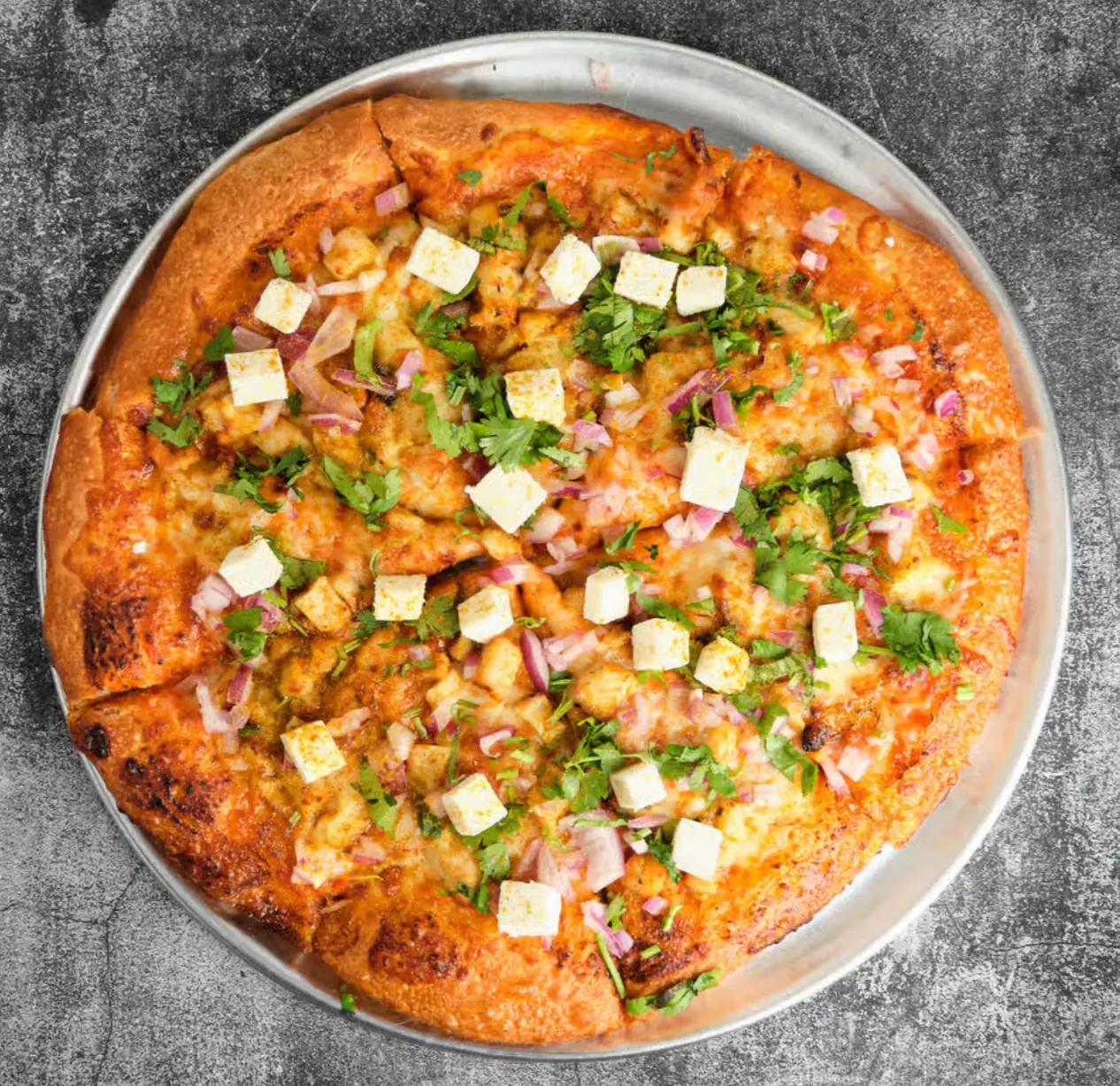 Tandoori paneer pizza topped with charred paneer, red onion and cilantro